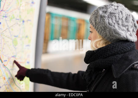 Signora guardando la mappa dei trasporti pubblici pannello. Foto Stock