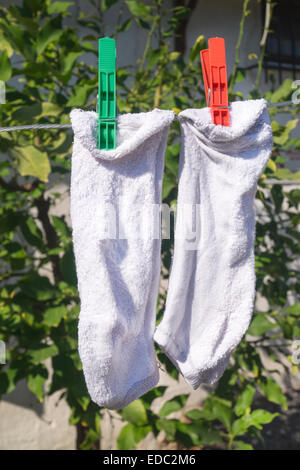 Due calze bianche appeso sulla corda Foto Stock