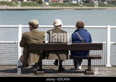 Tre senior citizen seduti in riva al mare a Clacton-on-Sea Regno Unito Inghilterra Foto Stock