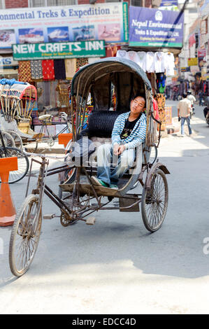 Stanco di risciò ciclo sonno del driver sul suo veicolo all'ingresso della zona di Thamel Kathmandu Foto Stock