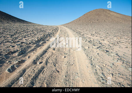 In un pneumatico di un veicolo le vie passando attraverso una desolata arido deserto roccioso paesaggio Foto Stock