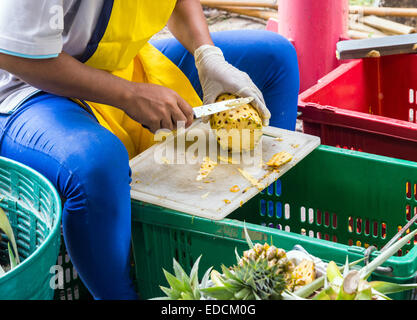 Il venditore è la pelatura ananas nel mercato della frutta fresca. Foto Stock