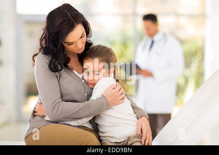 Triste giovane donna e la sua figlia di malati in attesa di checkup medico in camera del Foto Stock