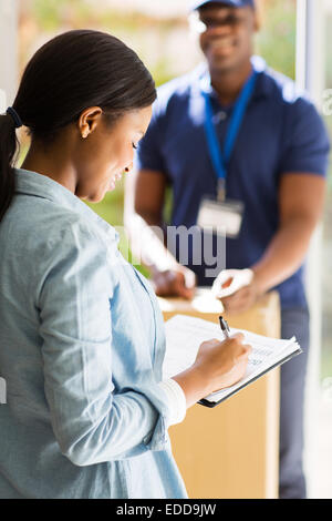 Felice donna africana la ricezione di post e firma documento Foto Stock