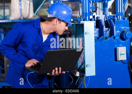 Tecnico industriale controllo scatola di distribuzione con computer portatile in fabbrica Foto Stock