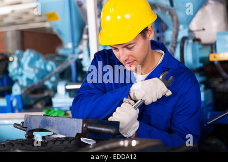 Repairman utilizzando chiave nella fabbrica gumboot Foto Stock