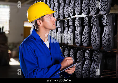 Bello operaio di fabbrica prendendo in gomma-stivali taglie in magazzino Foto Stock