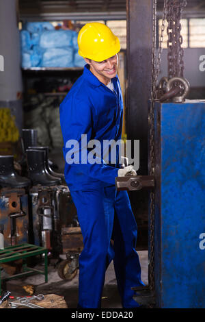 Lavoratore manuale utilizzando grande martello in officina Foto Stock