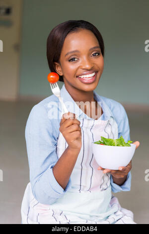 Attraente donna africana mangiare fresca insalata verde a casa Foto Stock