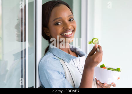 Bella ragazza africana insalata mangiare a casa Foto Stock