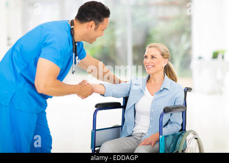 Gentile metà età medico saluto paziente disabile Foto Stock