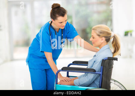 Caring giovane medico donna consolante un triste disabili paziente senior Foto Stock