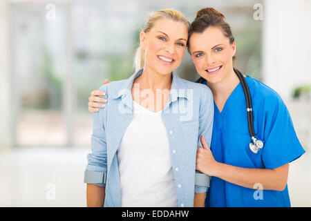 Caring giovane infermiere in piedi con paziente disabile in office Foto Stock