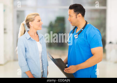 Bella Età media medico discute x-ray risultati al paziente Foto Stock