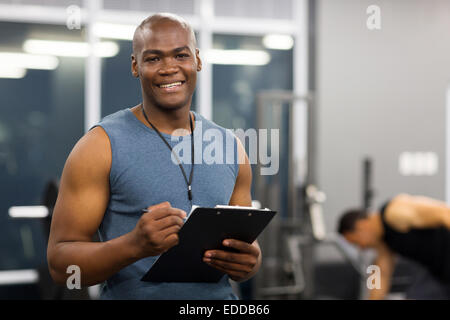 I giovani africani maschio americano personal trainer negli appunti di contenimento in palestra Foto Stock