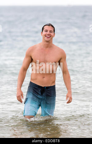 Sano giovane uomo a camminare in acqua di mare Foto Stock