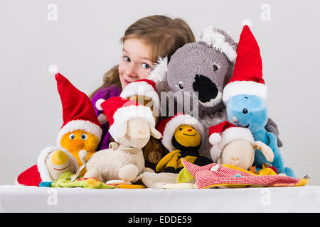 Ragazza 3 anni, con i giocattoli di peluche che indossa Santa Claus cappelli Foto Stock