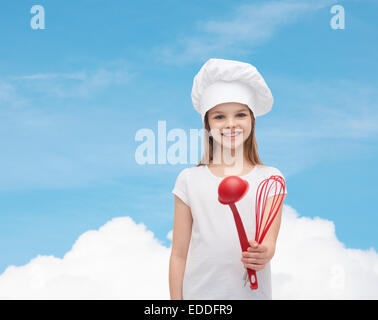 Ragazza sorridente in cook hat con siviera e frusta Foto Stock
