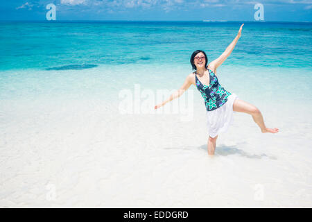 Maldive atollo di Ari, giovane donna in piedi in acqua su una gamba Foto Stock