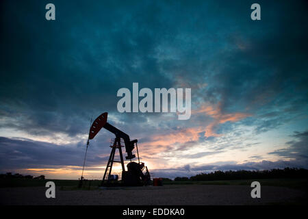 Un olio derrick, una testa pozzo che il braccio della pompa con il telaio, stagliano contro il cielo di sera. Il commercio di olio. Foto Stock