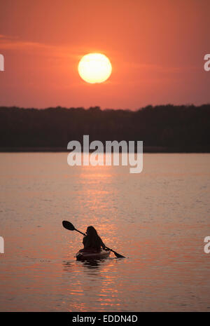 Kayaker al tramonto su un lago calmo. Foto Stock