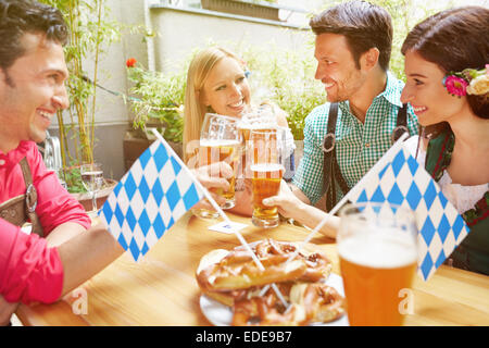 Happy amici di birra bavarese e giardino a bere birra in estate Foto Stock