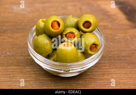 Olive farcite in ciotola sul tavolo di legno Foto Stock