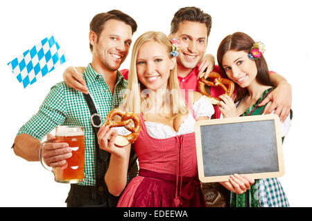 Gli uomini e le donne in Baviera con birra e pretzel tenendo una lavagna vuota Foto Stock