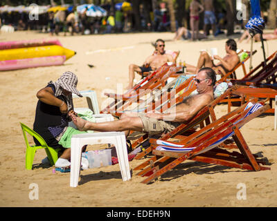 Pattaya, Chonburi, Thailandia. Il 6 gennaio, 2015. Un turista (destra) ottiene una pedicure da un fornitore sulla spiaggia di Pattaya. Il governo thailandese ha annunciato piani per ripulire la spiaggia di Pattaya, una delle più famose spiagge della Thailandia. Pattaya è circa 2,5 ore da Bangkok. Si prevede di ridurre il numero di ombrelloni e chaise longue i venditori sulla spiaggia e regolare i natanti ad uso personale e parasailing i venditori sulla spiaggia. Il governo ha già ripulito spiagge dell'isola di Phuket e Hua Hin. Credit: Jack Kurtz/ZUMA filo/Alamy Live News Foto Stock