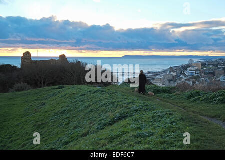 Hastings, East Sussex, 6 gennaio 2015. Regno Unito meteo. Dopo un opaco Rainy day, un dog walker si gode della vista dal Ladies' Parlour, come il sole tramonta su Hastings Castle and Beachy Head. Credito: Carolyn Clarke/Alamy Live News Foto Stock