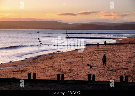 Exmouth, Devon, Regno Unito. 6 gennaio, 2015. Regno Unito meteo. Dog walkers al tramonto, Exmouth, Devon, Regno Unito il 6 gennaio 2015. Dog walkers esercitare i loro animali domestici nella gelida ROSY GLOW di un inverno tramonto sulla spiaggia di Exmouth Devon, Credito: dPAD/Alamy Live News Foto Stock