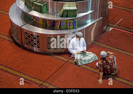 Musulmani smartphone il controllo presso la Moschea Istiqlal / Masjid Istiqlal, più grande moschea in Indonesia e nel Sud Est asiatico a Giacarta Foto Stock