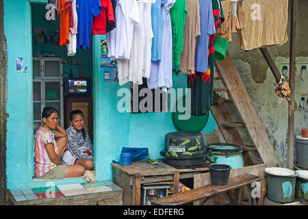 Madre indonesiano e la figlia a casa con lavanderia essiccazione su stendibiancheria in Kota / Old Batavia, Java, Indonesia Foto Stock