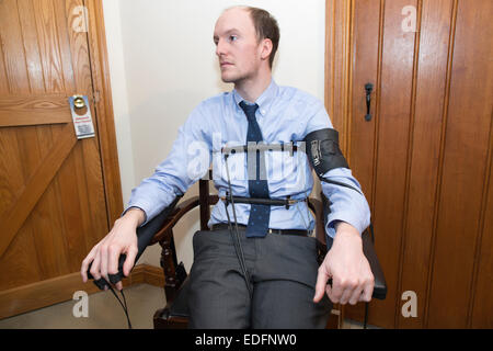 Uomo di essere esaminato usando un test di poligrafo lie detector macchina che confronta le risposte a domande selezionate per ottenere la verità Foto Stock