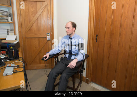 Uomo di essere esaminato usando un test di poligrafo lie detector macchina che confronta le risposte a domande selezionate per ottenere la verità Foto Stock