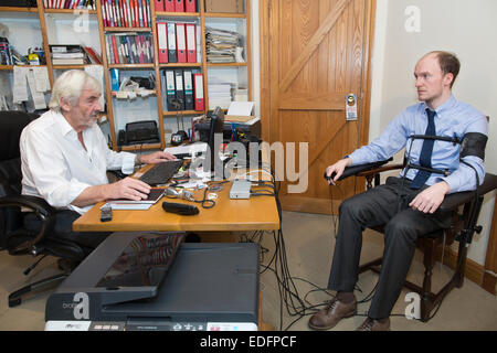 Uomo di essere esaminato usando un test di poligrafo lie detector macchina che confronta le risposte a domande selezionate per ottenere la verità Foto Stock