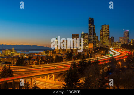 Il traffico di Freeway e skyline del centro al tramonto, Seattle, Washington, Stati Uniti d'America Foto Stock