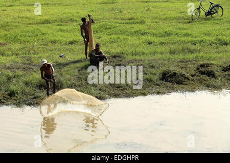 CHITWAN, Nepal - 14 ottobre: pescatore locale genera un cast netti per la pesca in un stagno accanto al fiume Terai su ottobre 14,2012 Foto Stock