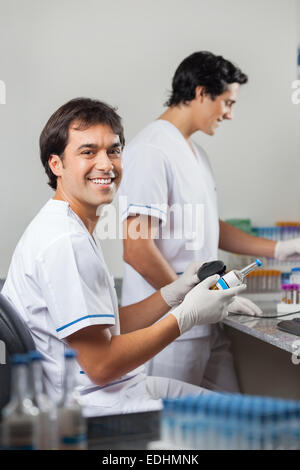 Tecnico utilizzando il lettore di codici a barre a scansione il campione in laboratorio Foto Stock