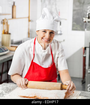 Donna sorridente chef di laminazione il foglio di pasta al banco Foto Stock