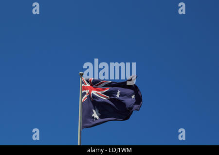 La fotografia di una bandiera australiana al vento contro uno sfondo di cielo blu. Foto Stock