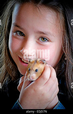 Un sorridente ragazza giovane trattiene il suo animale domestico hamster fino per la fotocamera Foto Stock