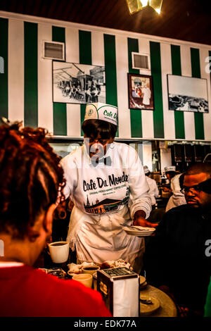 Senior cameriera nero serve caffè e beignets nel Cafe du Monde, New Orleans LA Foto Stock