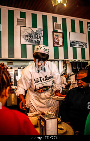 Senior cameriera nero serve caffè e beignets nel Cafe du Monde, New Orleans LA Foto Stock