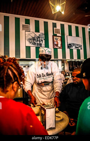 Senior cameriera nero serve caffè e beignets nel Cafe du Monde, New Orleans LA Foto Stock