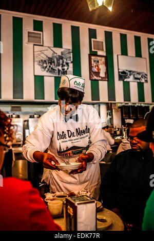 Senior cameriera nero serve caffè e beignets nel Cafe du Monde, New Orleans LA Foto Stock