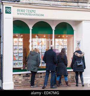 Le persone che cercano nella finestra di Durrants agente immobiliare a Southwold , Suffolk , Inghilterra , Inghilterra , Regno Unito Foto Stock