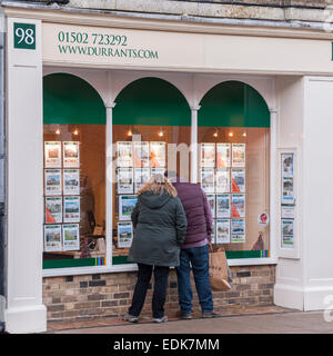 Le persone che cercano nella finestra di Durrants agente immobiliare a Southwold , Suffolk , Inghilterra , Inghilterra , Regno Unito Foto Stock
