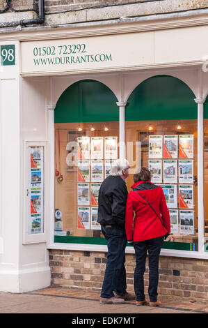Le persone che cercano nella finestra di Durrants agente immobiliare a Southwold , Suffolk , Inghilterra , Inghilterra , Regno Unito Foto Stock