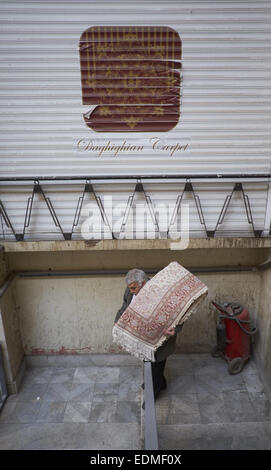 Tehran, Iran. Il 7 gennaio, 2015. 7 gennaio 2015 - Teheran, Iran - Un lavoratore iraniano che porta una mano persiano tappeti tessuti a Teheran il tappeto Bazaar. Morteza Nikoubazl/ZUMAPRESS © Morteza Nikoubazl/ZUMA filo/Alamy Live News Foto Stock